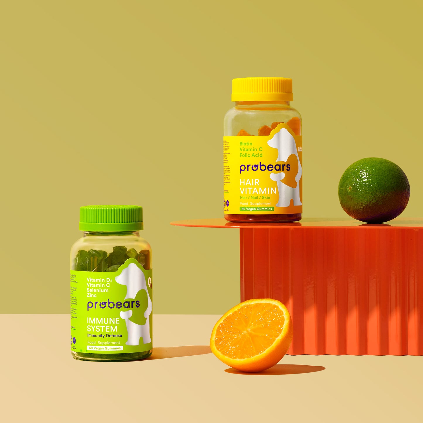 Kombipackung von Probears Immune System und Hair Vitamin, platziert neben frischen Orangen als Symbol für die natürlichen Vitaminquellen in den Produkten.