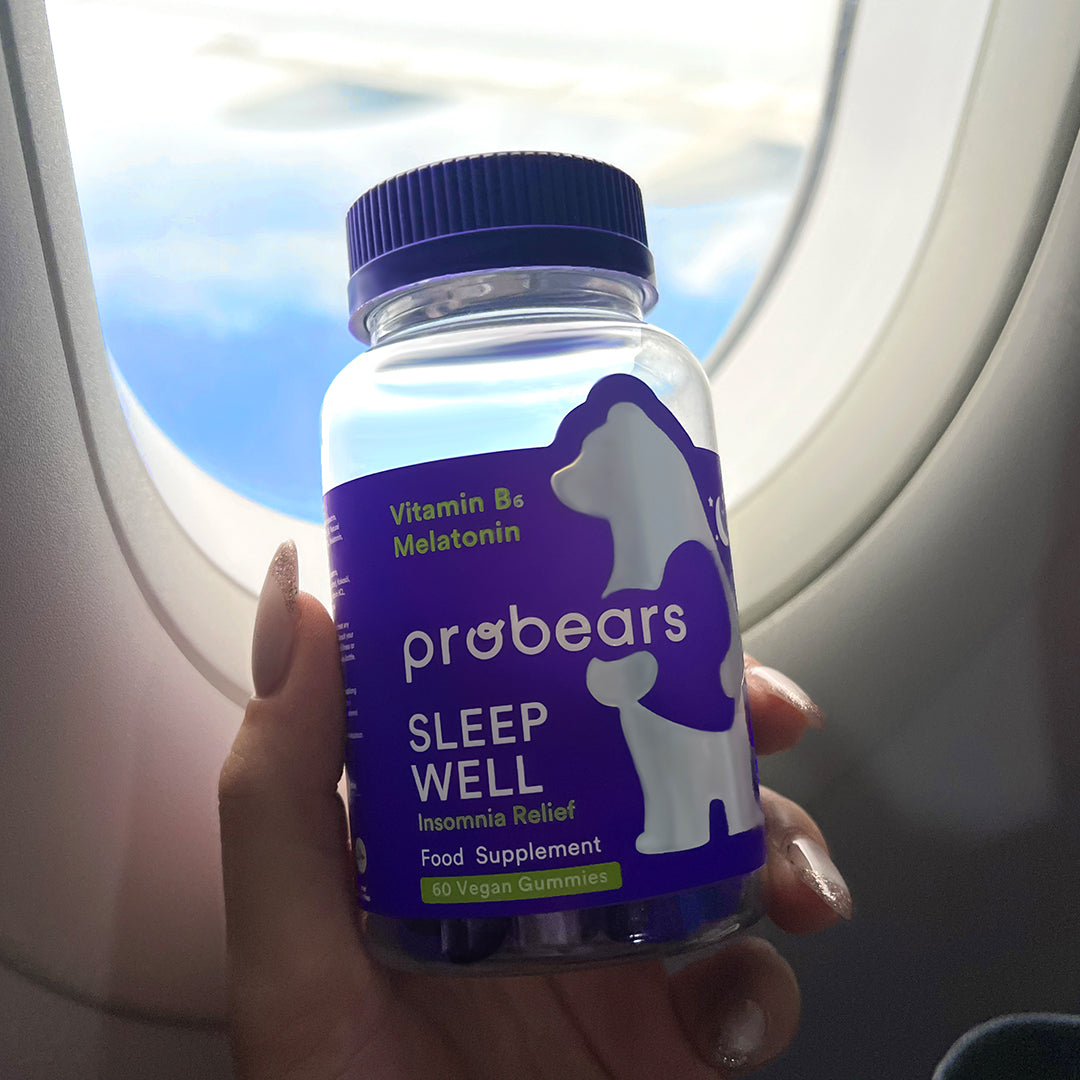 Flasche von Probears Sleep Well Gummibärchen, wird in einem Flugzeug präsentiert, ideal für Ruhe und Regeneration auch unterwegs.