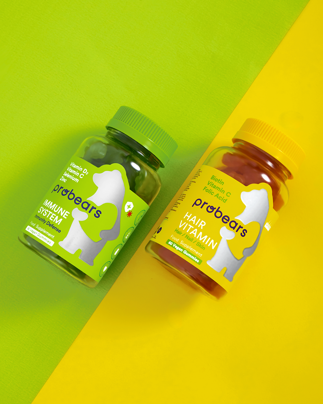 Leuchtendes Set von Probears Immune System und Hair Vitamin Gummibärchen, farbenfroh präsentiert auf gelb-grünem Hintergrund für Gesundheit und Wohlbefinden.